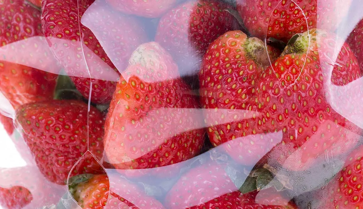 Close-up of bright red strawberries inside a clear plastic clamshell container.