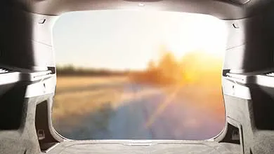 View from inside an open car trunk, looking out at a bright, blurry landscape.