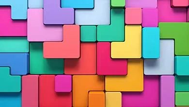 Brightly colored 3D geometric blocks in pink, purple, blue, teal, green, yellow, orange, and red, arranged in an interlocking puzzle pattern.