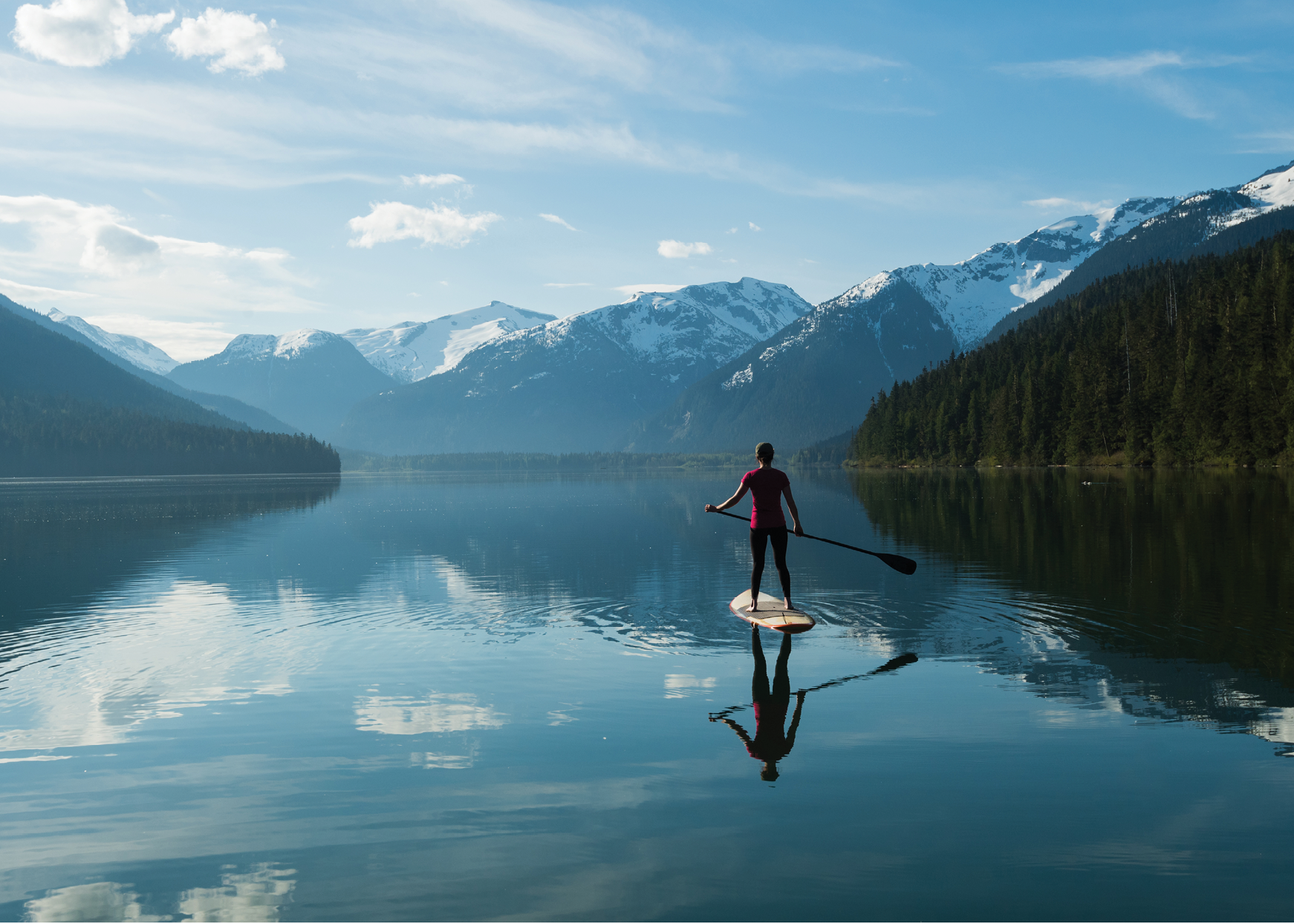 Woman stand up paddle boarding on a pristine mountain lake